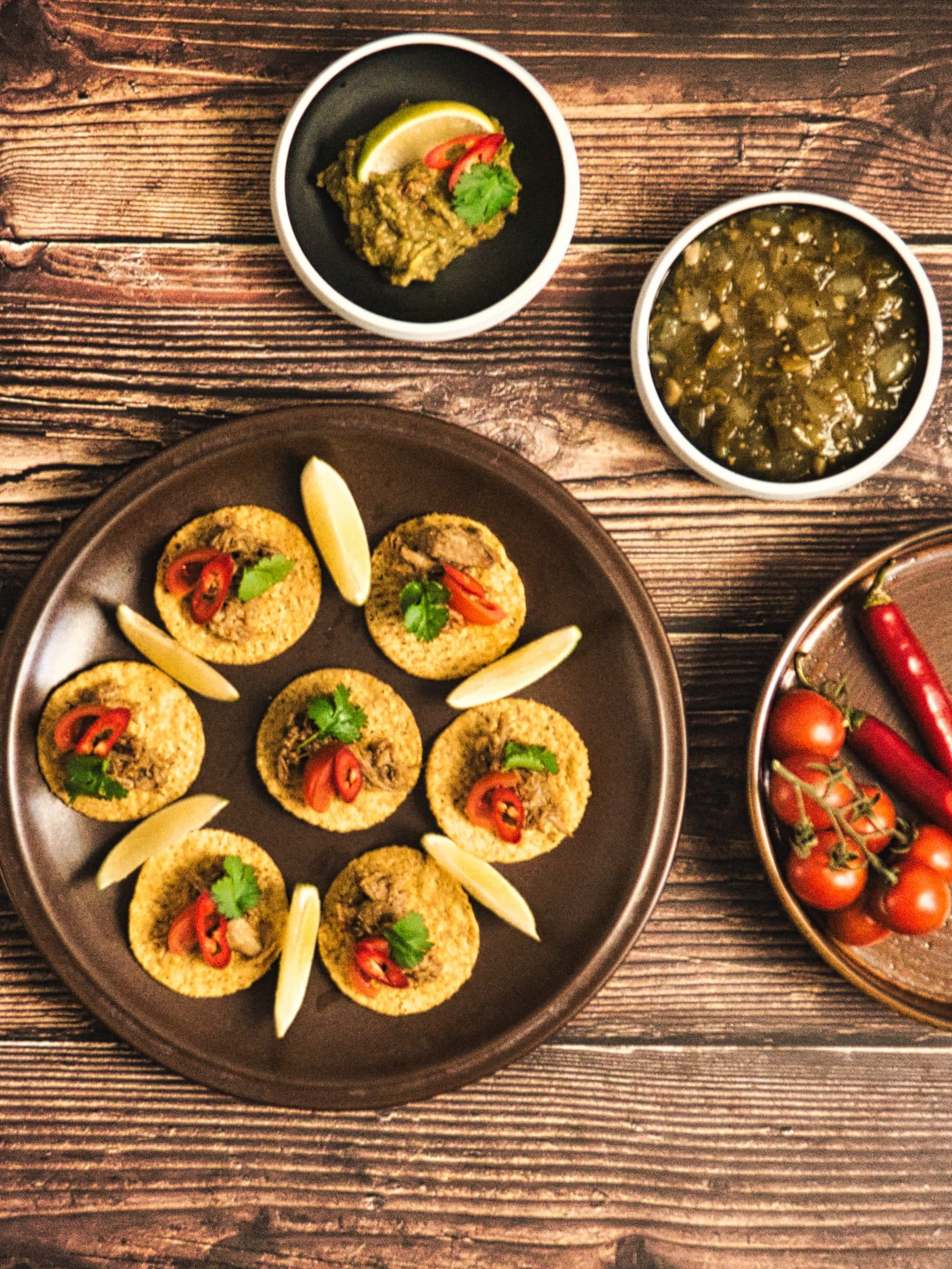 En skål med saftigt og mørt svinekød braiseret til perfektion. Kødet serveres med frisk koriander, hakket løg og limebåde, klar til at blive fyldt i tacos eller brugt i andre mexicanske retter.